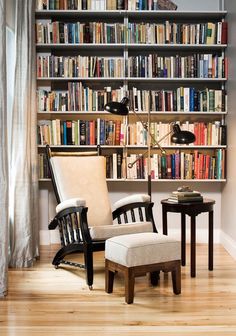 a chair and table in front of a bookshelf filled with lots of books