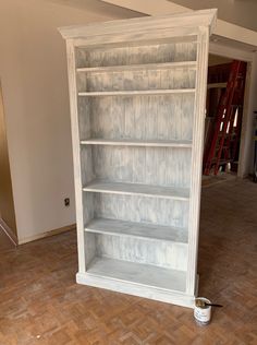 a white painted bookcase in an unfinished room