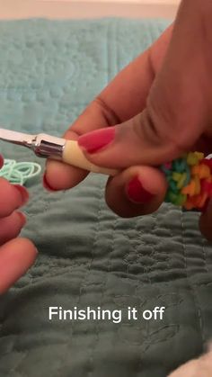 two hands holding crochet hooks on a bed with the words finishing it off