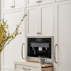 a kitchen with white cabinets and drawers has a coffee maker on the counter in front of it