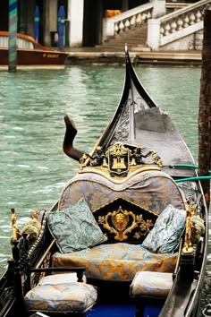 a gondola in the water with pillows on it's back and seat