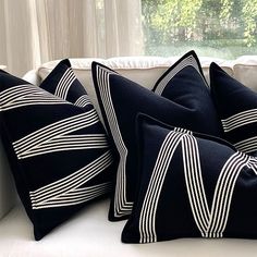 four black and white pillows sitting on top of a couch in front of a window