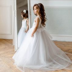 Ivory Flower Girl Dress - a divine masterpiece crafted with love. The bodice boasts Ivory Bridal lace, adorned with a delicately sewn waist sash. The enchanting V-neck back flaunts an open design graced by a concealed zipper and a grand bow. The resplendent skirt features five layers of ethereal tulle, exuding grace with every step. This dress is a symphony of artistry, ideal for weddings, christenings, baptisms, and all treasured occasions. Its versatility shines as a first communion dress, tod White Tulle Skirt Ball Gown For Baptism, White Ball Gown Tutu Dress For First Communion, White Tulle Ball Gown For Baptism, White Princess Baptism Dress With Tulle Skirt, White Tulle Princess Dress For Wedding, White Tulle Wedding Princess Dress, Princess Tulle Wedding Dress For First Communion, First Communion Ball Gown With Tulle Skirt For Baptism, Tulle Princess Wedding Dress For Confirmation