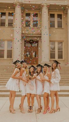 a group of young women standing next to each other in front of a building with confetti