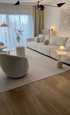 a living room with white furniture and wood floors