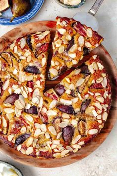 a sliced pizza on a wooden platter next to other food