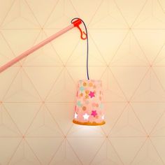 a pink lamp hanging from the ceiling with stars on it and a stick sticking out of it