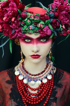 a woman with flowers on her head and necklaces around her neck, wearing red jewelry