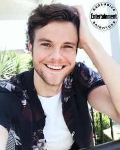 a young man is smiling and posing for the camera with his hand on his head