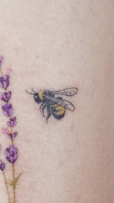 a bee sitting on top of a purple flower next to a small branch with leaves