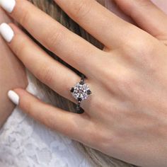 a close up of a person's hand with a ring on their finger and a white manicure