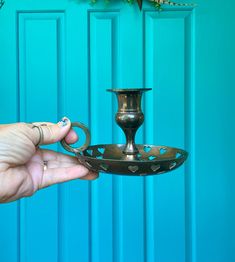 a person holding a metal candle holder in front of a blue door