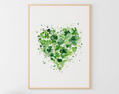 a heart made up of green leaves on a white wall with a wooden frame in the corner