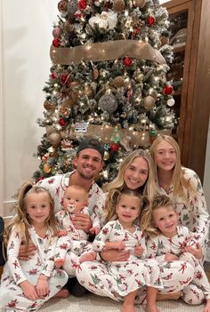 a family wearing matching christmas pajamas in front of a christmas tree