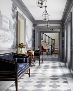 an image of a hallway with blue couches and chandelier hanging from the ceiling