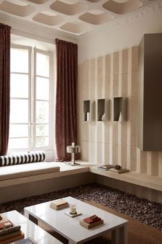 a living room filled with furniture next to a window covered in red and white curtains