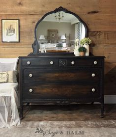 a dresser and mirror in a room with wood paneling on the wall behind it