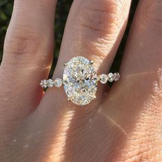 a person's hand with a diamond ring on top of their finger and the other hand holding an engagement ring