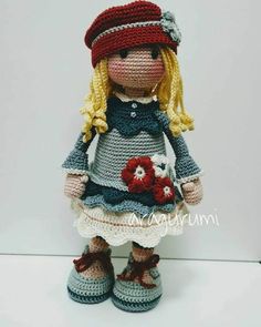 a crocheted doll is dressed in a dress and hat with flowers on it