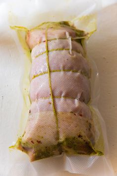 an uncooked ham wrapped in plastic on a white surface with a yellow strip