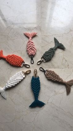 several different colored fish shaped key chains on a white counter top, all in the shape of a circle