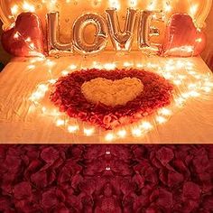 a bed covered in red roses and lights with the word love spelled out on it