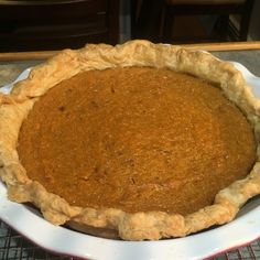 a pie sitting on top of a white plate next to a metal rack filled with food