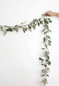 someone is making a garland out of eucalyptus leaves