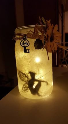 a mason jar with some flowers in it on a table next to a light bulb