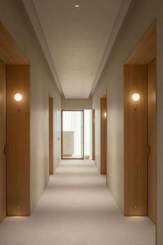 an empty hallway with wooden doors and white carpet