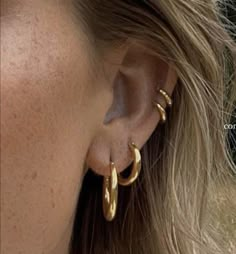 a close up of a person wearing large gold hoop earrings on their ears