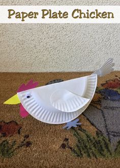 a paper plate chicken sitting on top of a carpet next to a wall with the words paper plate chicken above it