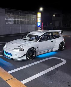 a white car is parked on the street at night