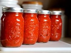 six jars of red sauce lined up on a shelf