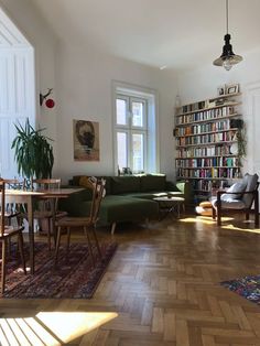 a living room filled with lots of furniture and bookshelves next to a window