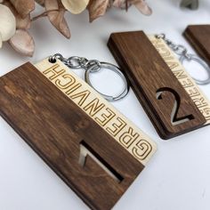 two wooden keychains with numbers on them sitting next to some flowers and leaves