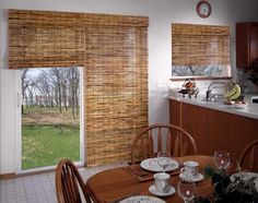 a dining room table and chairs in front of a window with bamboo blinds on the windowsill