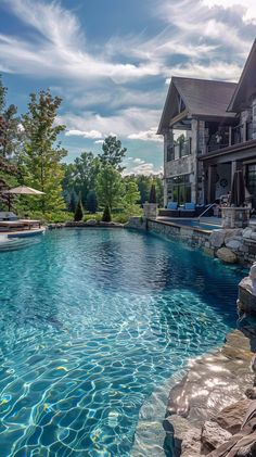 an outdoor swimming pool surrounded by rocks and water features a large stone patio with lounge chairs