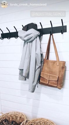 a coat rack with two coats hanging on it and some baskets next to it in front of a white wall