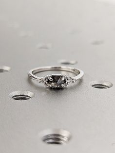 a diamond ring sitting on top of a metal surface with holes in the floor behind it