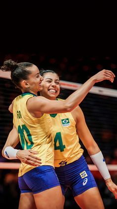 two women in yellow and blue uniforms are hugging each other on the volleyball court with hearts floating above them