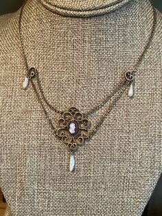 "c1910 Late Art Nouveau gold filled festoon necklace featuring a carved agate cameo set in a scrollwork frame with dog tooth pearl dangles. The piece is in amazing condition. All original. Clasp works well. The setting with cameo and pearl is just shy of 2\" in height. 16.25\" in length. Meant to wrap around the neck." Victorian Filigree Necklaces For Vintage Events, Victorian Filigree Necklace For Vintage Events, Victorian Pendant Necklace For Vintage Events, Victorian Cabochon Pendant Necklace, Victorian Pendant Necklace With Cabochon, Antique Cabochon Necklace For Collectors, Victorian Bronze Necklaces With Intricate Design, Antique Gold Art Nouveau Jewelry For Formal Occasions, Antique Gold Necklace For Vintage Events