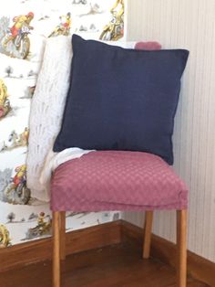 a chair with a pillow on top of it in front of a wallpapered background