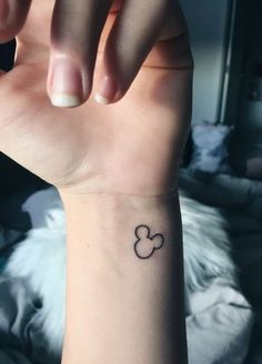 a woman's wrist with a small mickey mouse tattoo on the left side of her arm