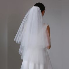 the back of a bride's wedding dress with a veil on her head and shoulder