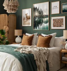 a bedroom with green walls and pictures on the wall above the bed, along with two lamps