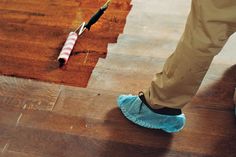 a person standing on top of a wooden floor next to a brush and an umbrella