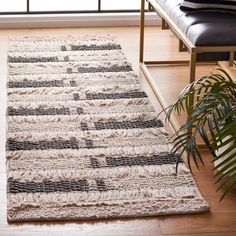 a large rug is on the floor in front of a chair and window with a plant