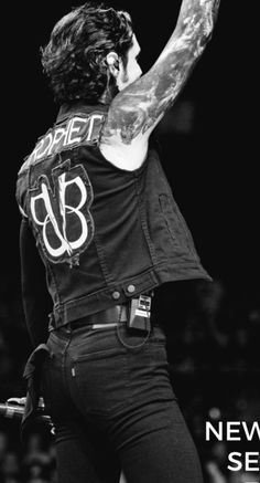 a black and white photo of a man with tattoos on his arm holding a microphone