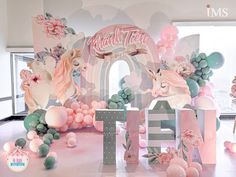 there is a pink and white unicorn themed room with balloons on the floor, flowers in the air, and letters that spell out hello